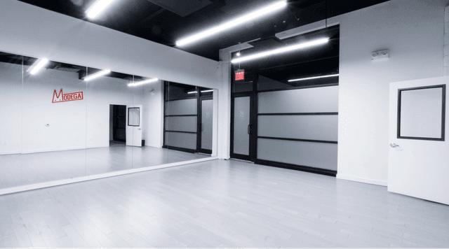 Dance studio with bright overhead lights, making it very bright even though it is nighttime as revealed by the opaque windows